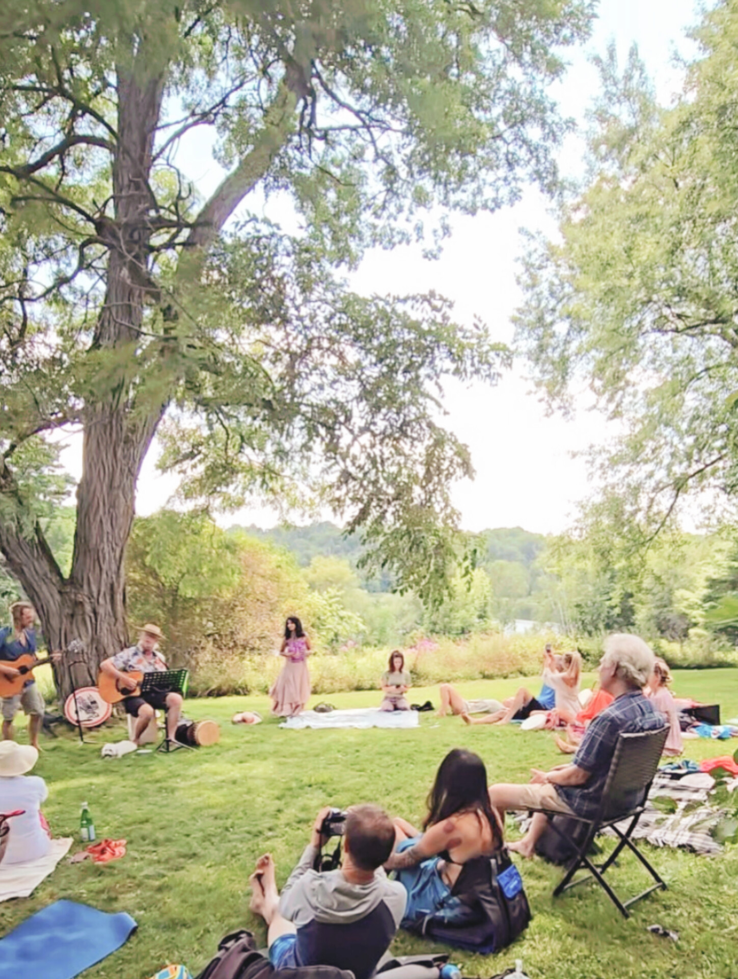 Community singing circle gathering outdoors under a tree