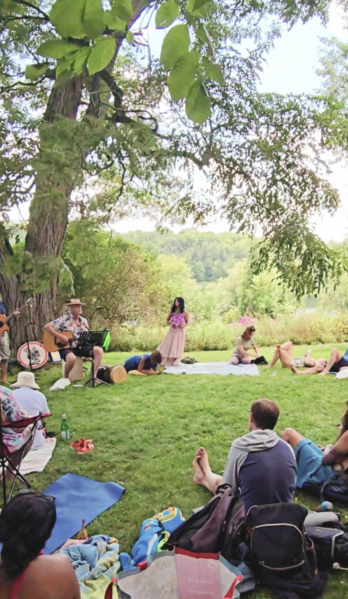 Community singing circle gathering outdoors under a tree