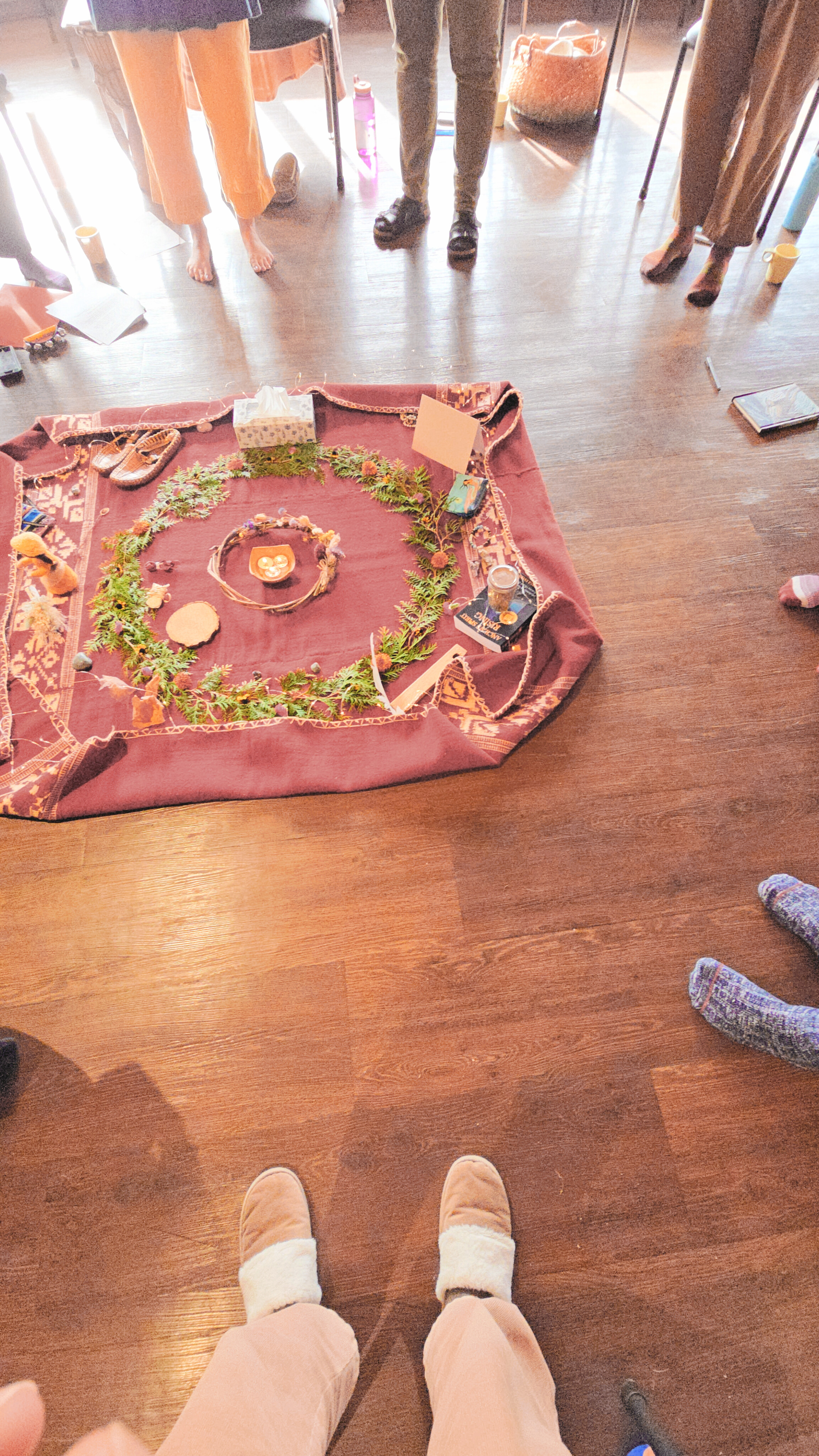 Overhead view of a singing circle with ceremonial cloth and greenery spiral